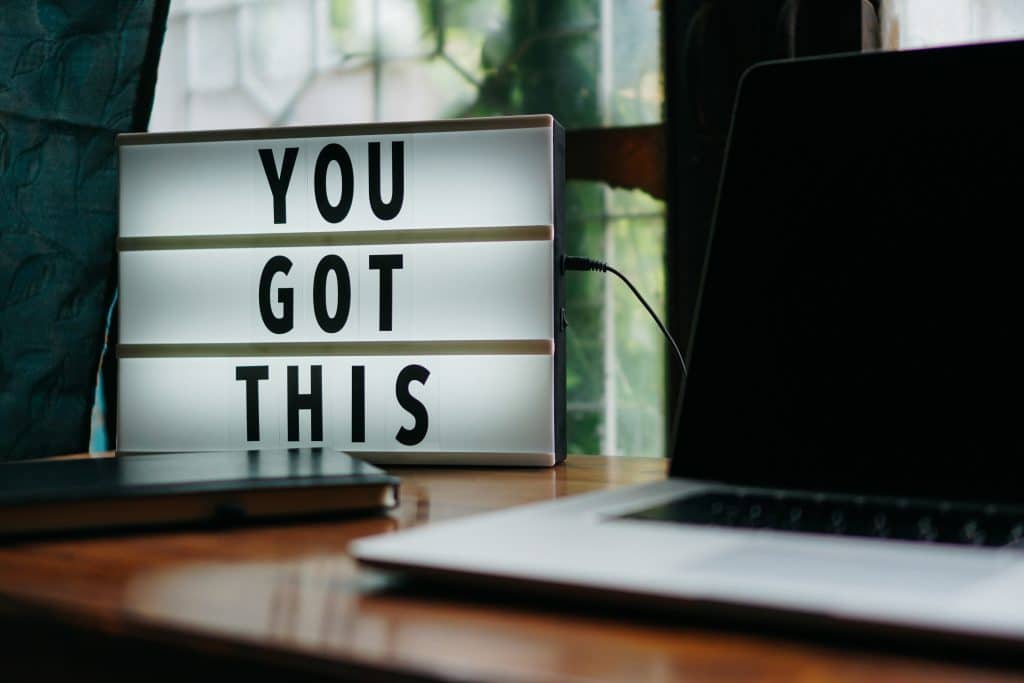 'You got this' sign sitting on desk next to computer and planner