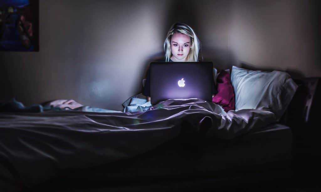 Procrastination - Woman sitting in the dark on her computer