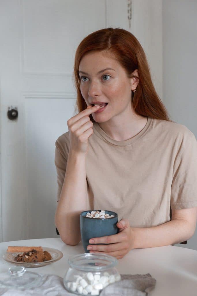 Woman with red hair eating marshmallows with hot cocoa