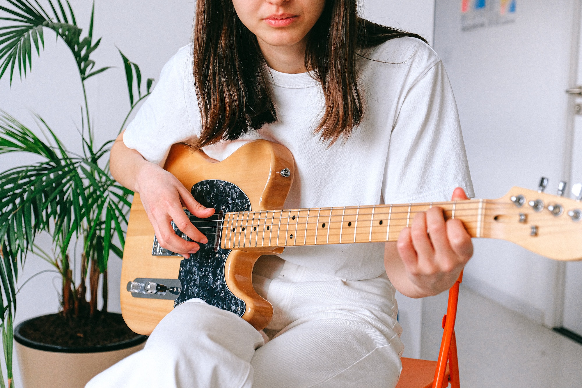 Woman practising guitar at home as hobby