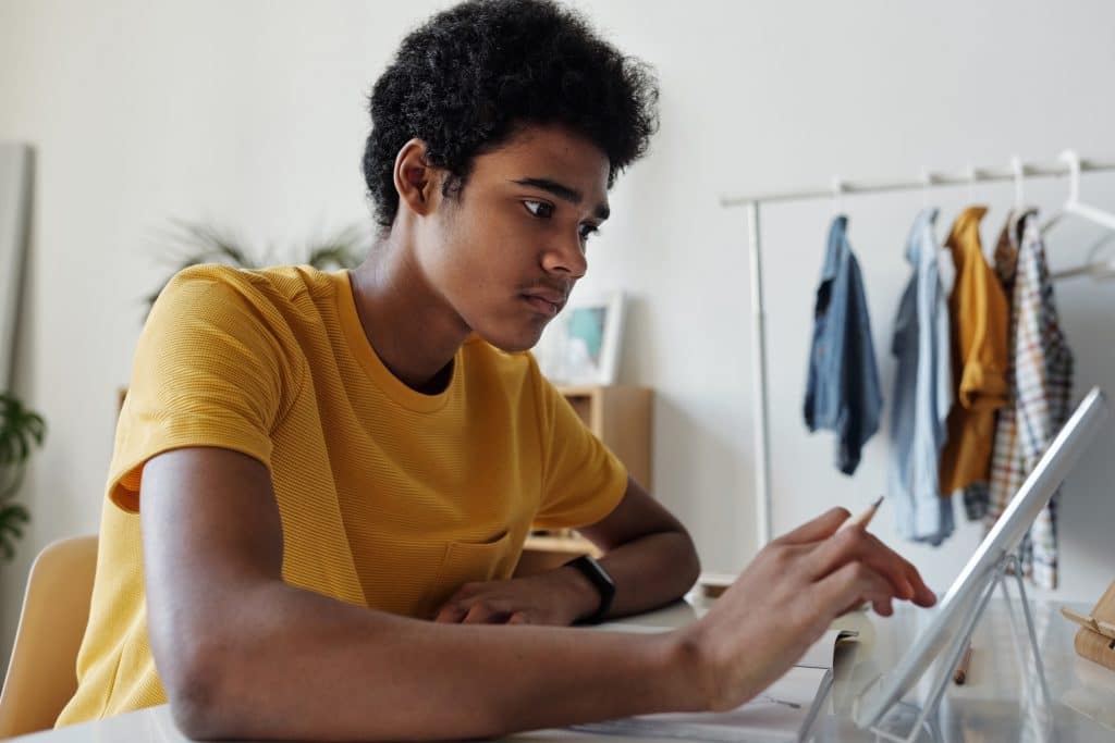 Teen boy studies using tablet ipad device