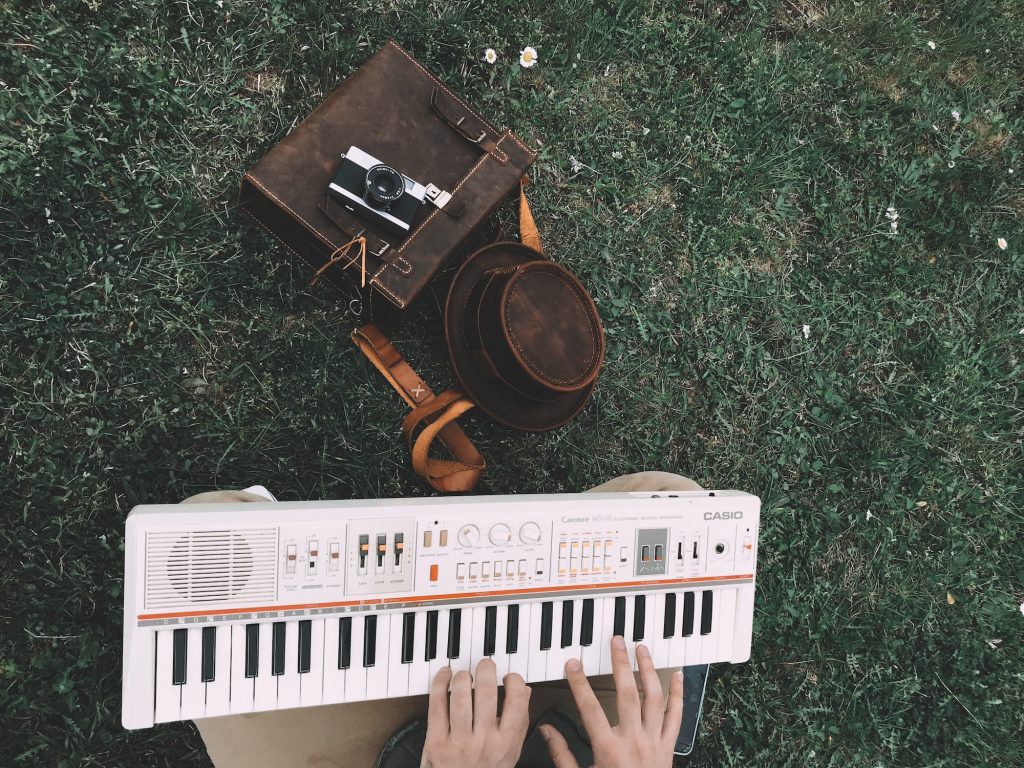 person playing casio keyboard outdoors with analog camera