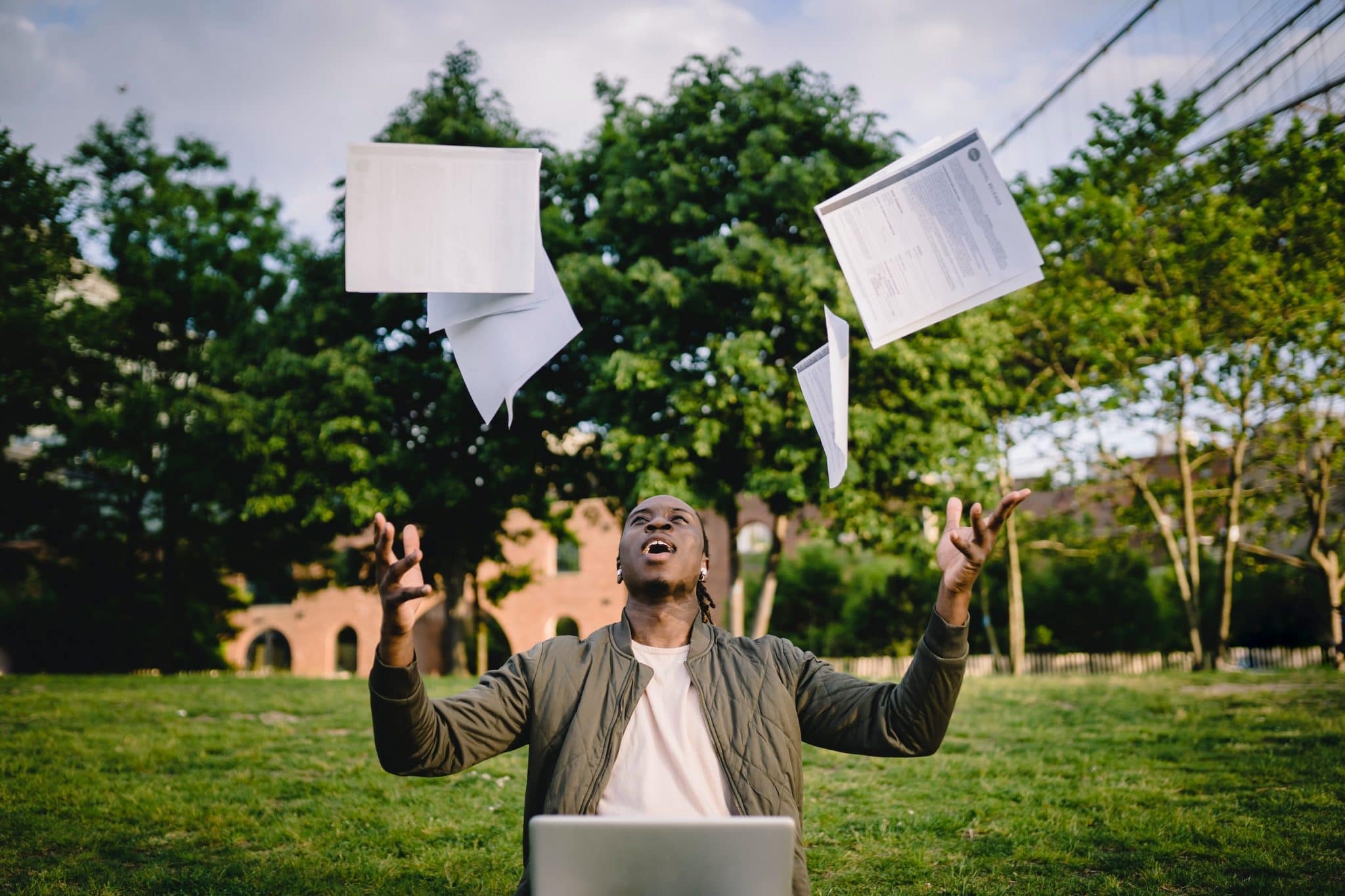 College student celebrating success throwing papers in air