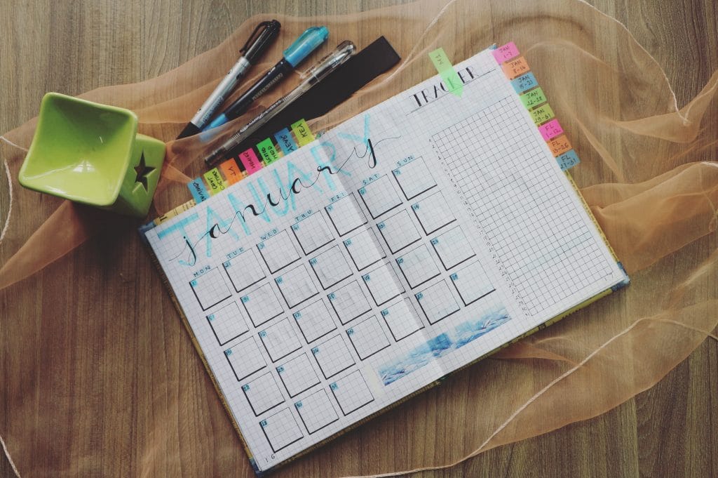 monthly planner notebook pens on desk with candle