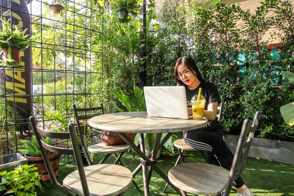 woman working outside with laptop in green garden space