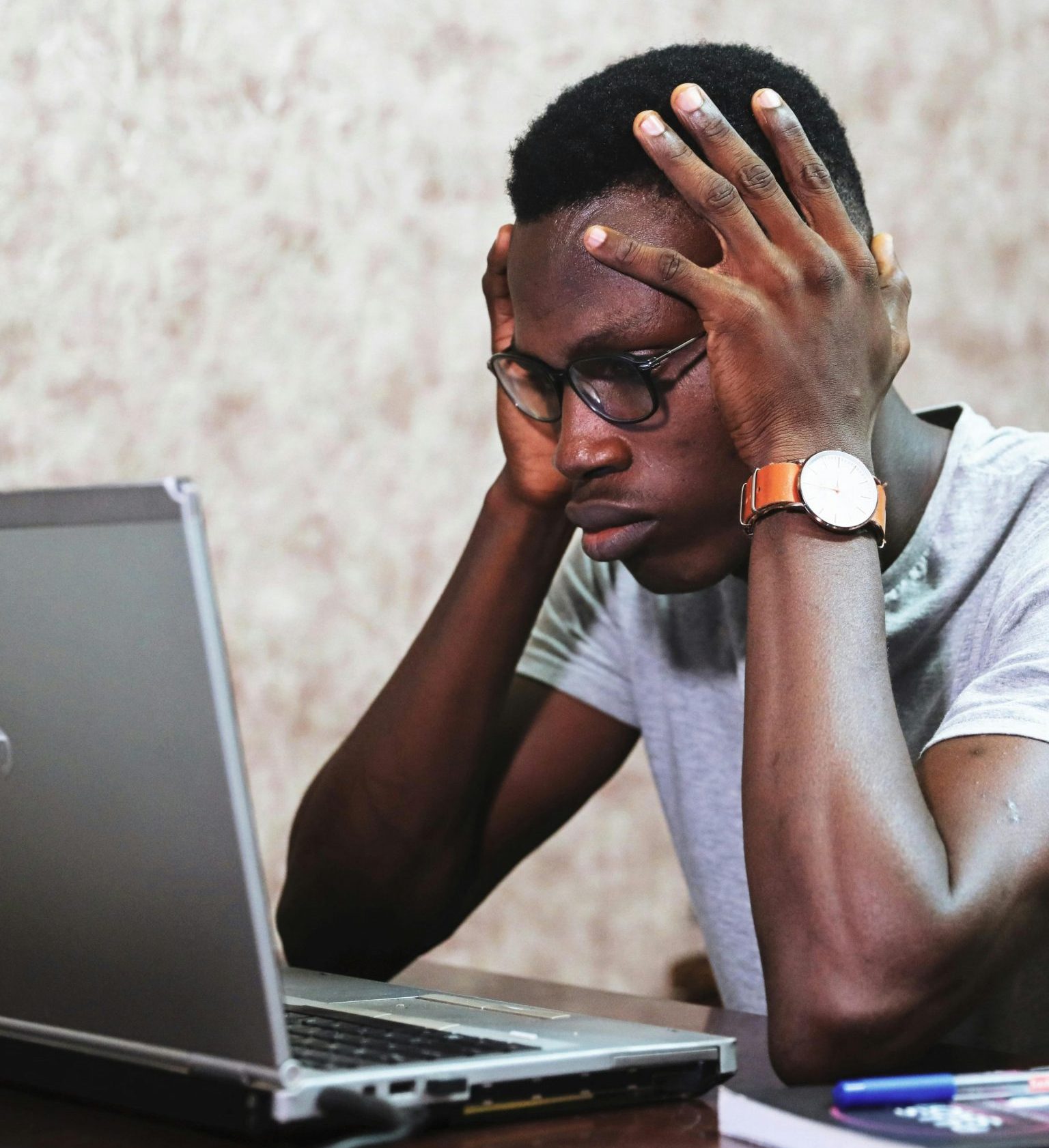 Image portrays a stressed man with hands on head, gazing at a screen, illustrating the mental health strain of prolonged screen use, potentially leading to increased anxiety and cognitive overload