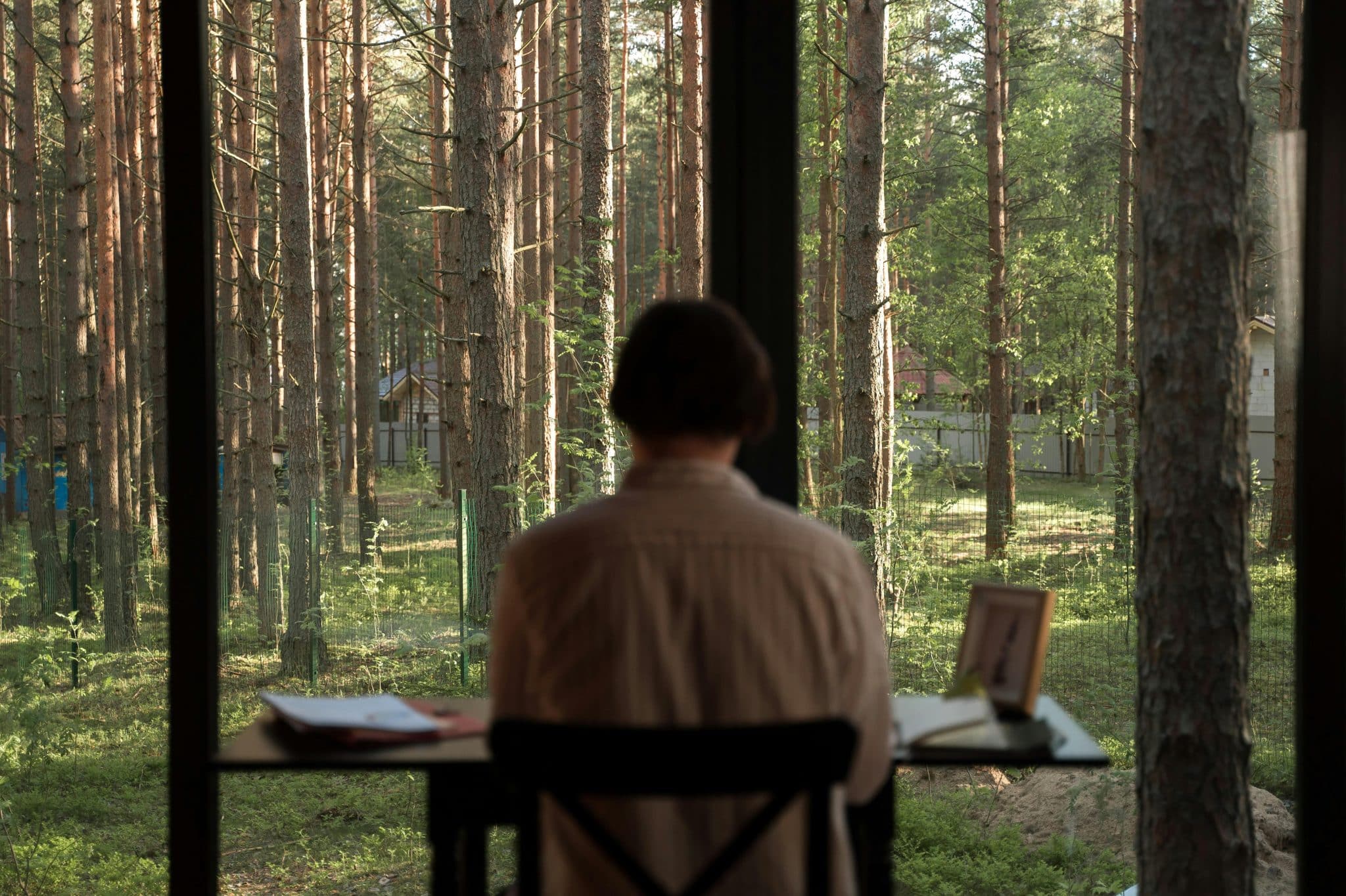 A person wearing headphones, working on a laptop in a serene natural setting.