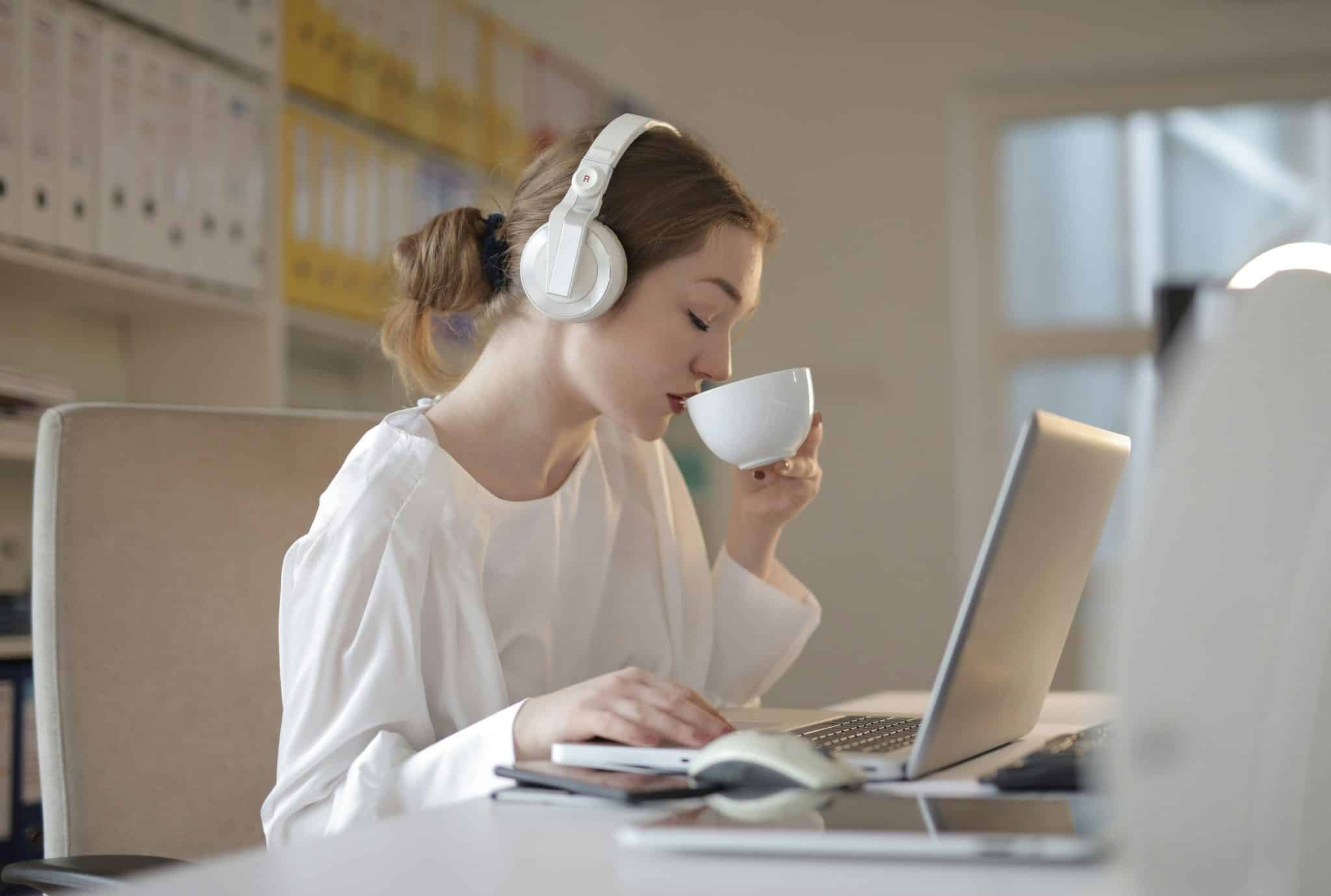 Focused woman wearing headphones, working on laptop.