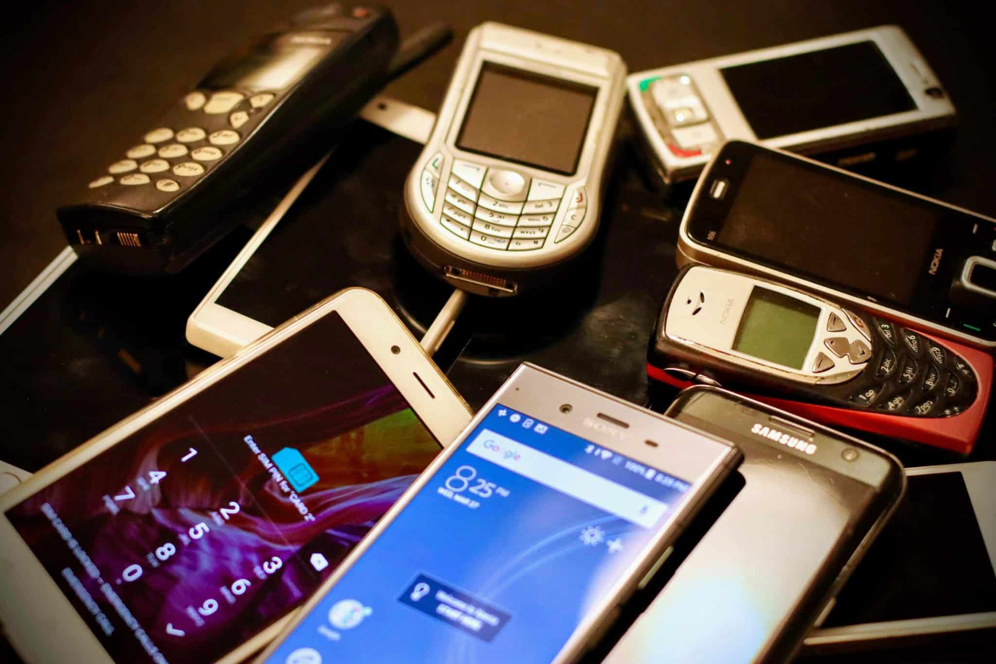 Pile of outdated smartphones representing the overload of digital devices before choosing a digital detox in 2025.
