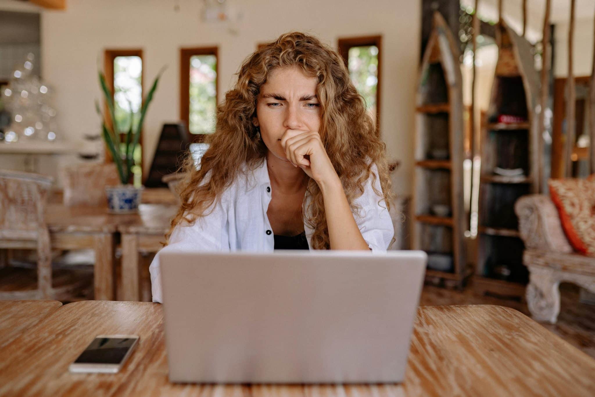A woman thinking deeply while looking at her laptop to enable focus maxxing.